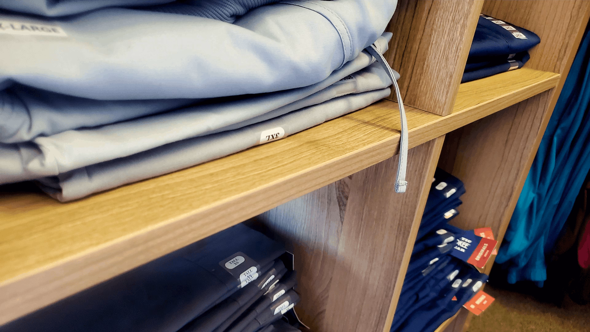 Shelves with neatly folded clothing in different colors and sizes in a retail store.