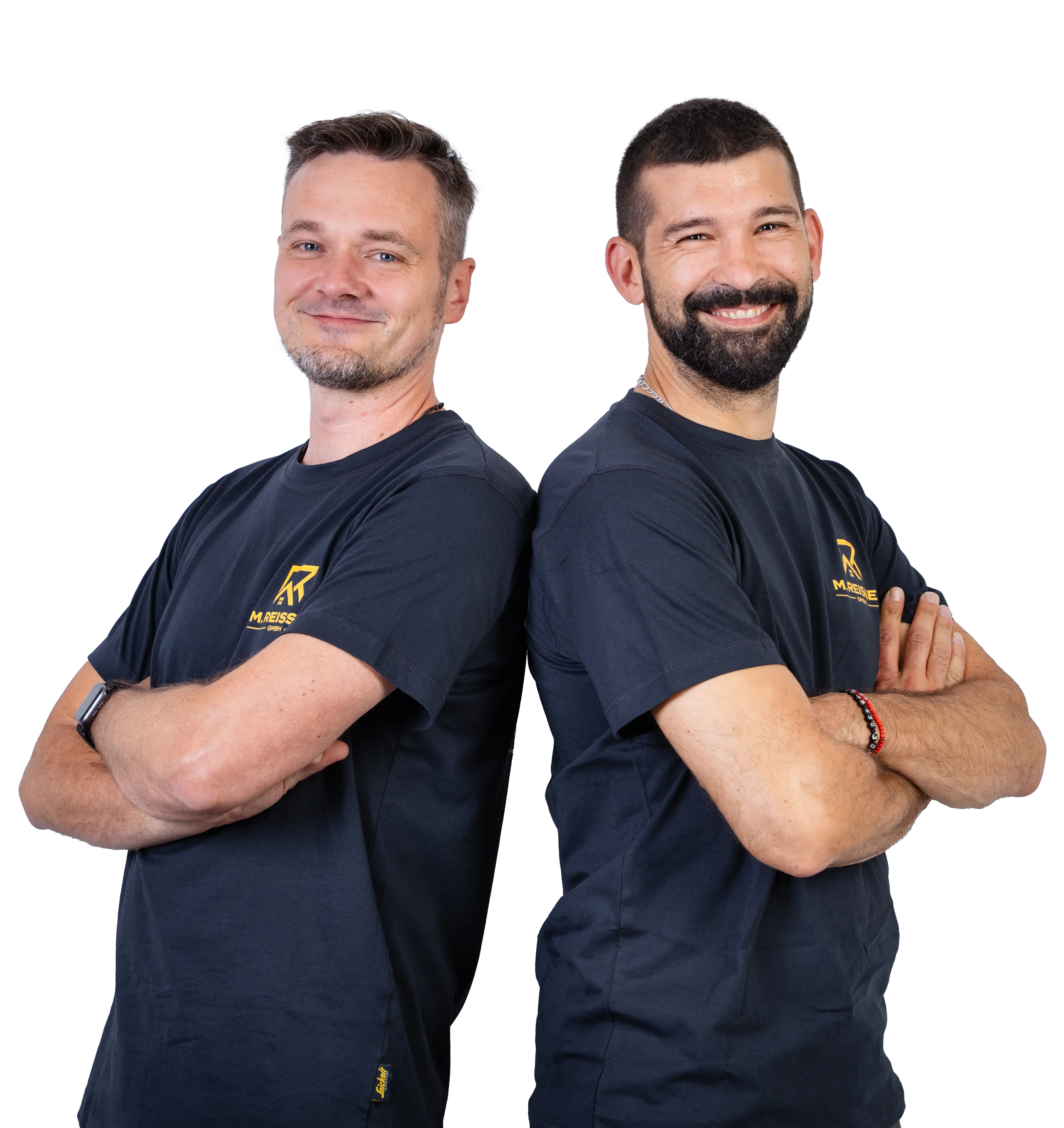 Zwei Männer stehen Rücken an Rücken mit verschränkten Armen und lächeln in schwarzen M. Reisser Shirts.