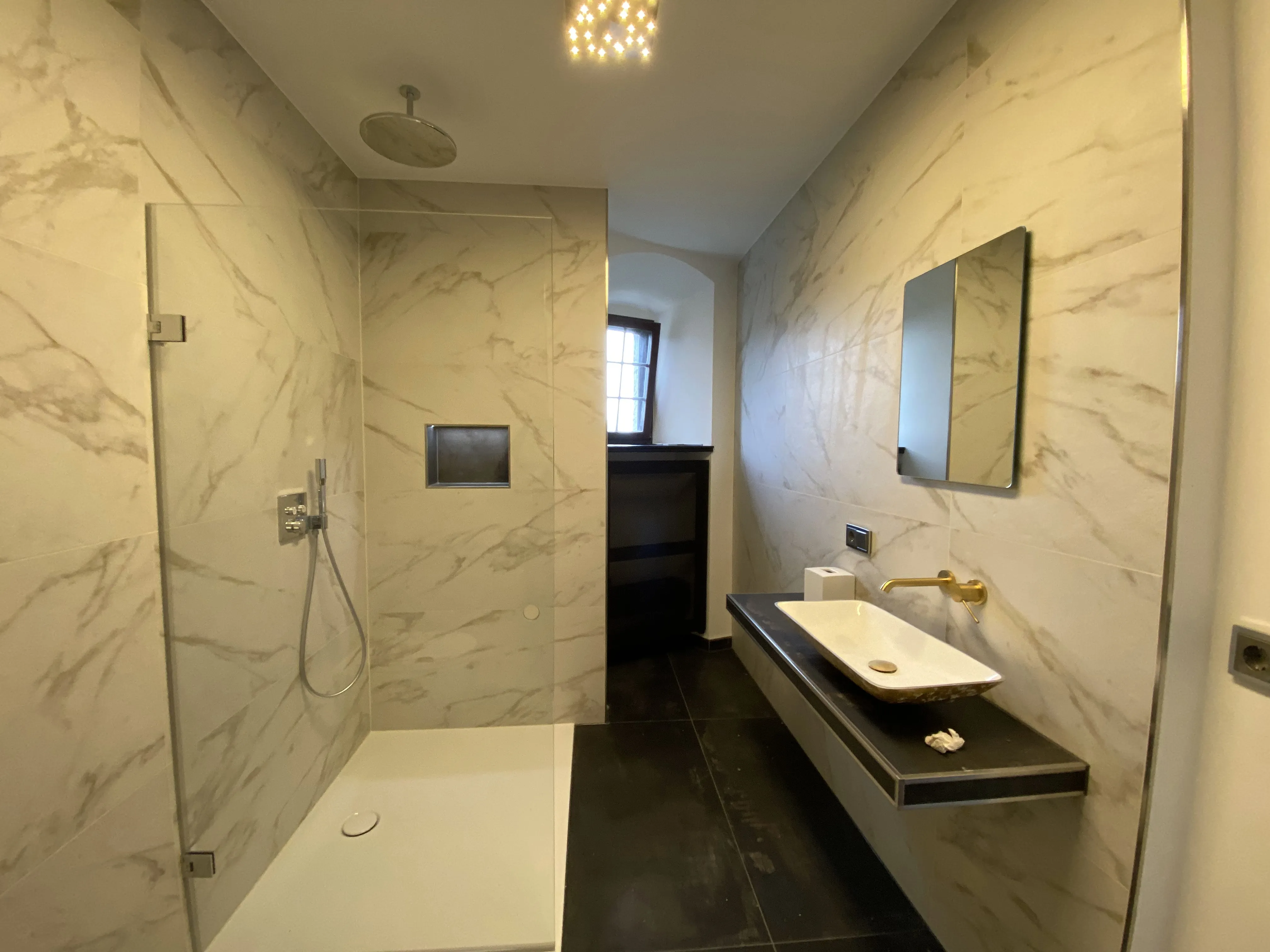 Modernes Badezimmer mit begehbarer Dusche, rechteckigem Waschbecken und Marmorfliesen an Wänden.