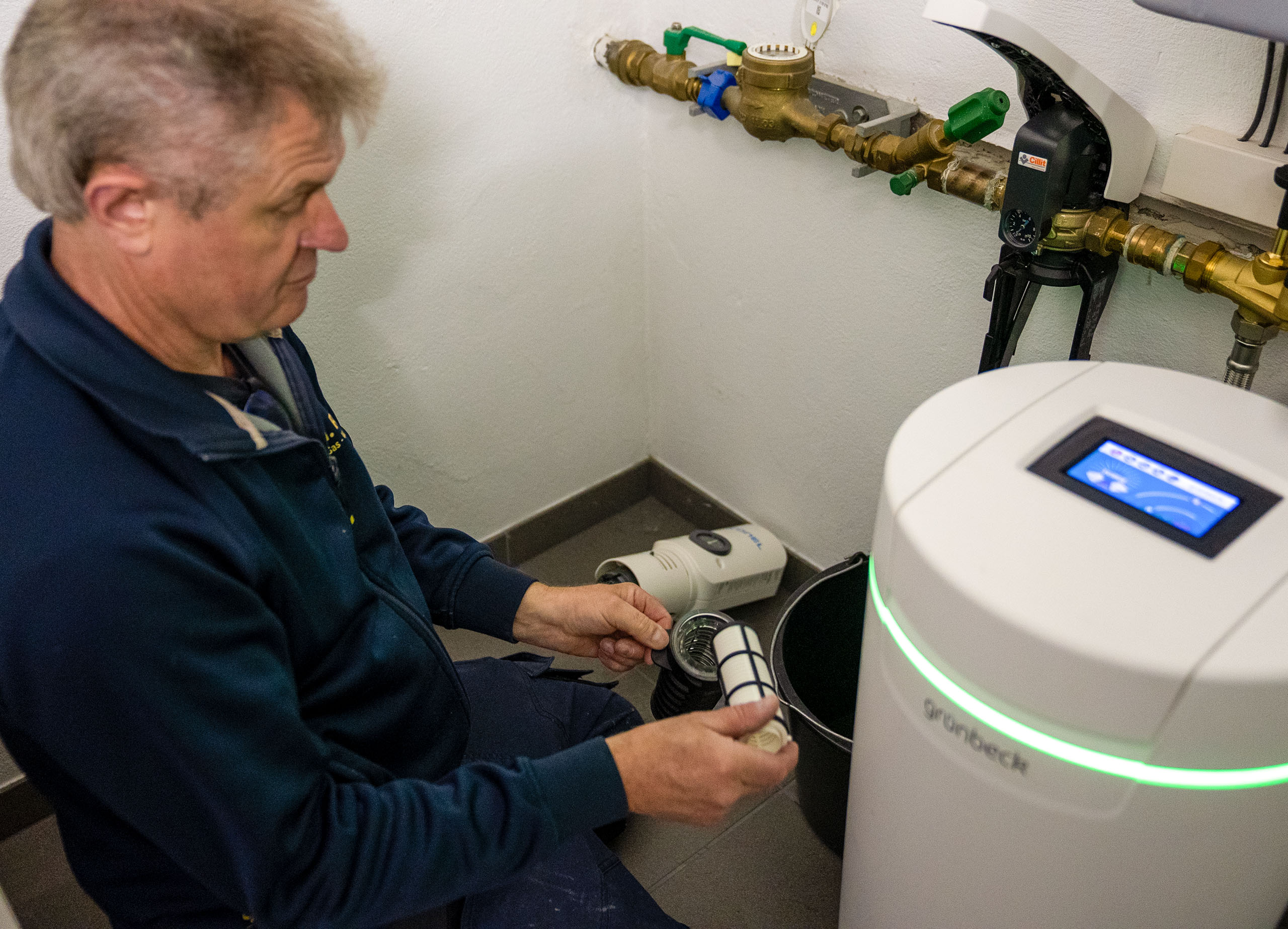 Heizungsanlage mit isolierten Rohren, Steuergerät und zwei großen grauen Tanks in einem technischen Raum.