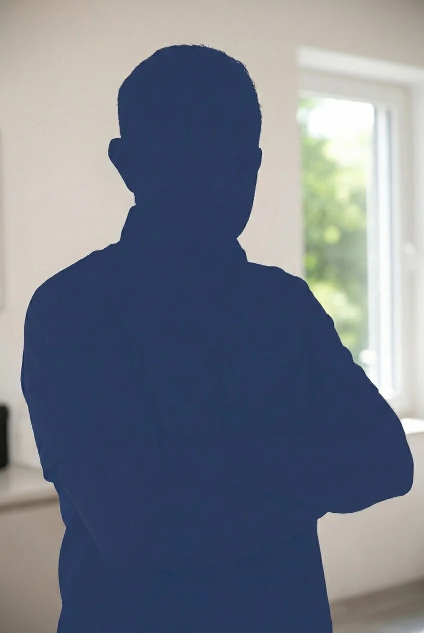 Schattenriss eines Mannes mit verschränkten Armen vor einem Fenster in einem Raum.