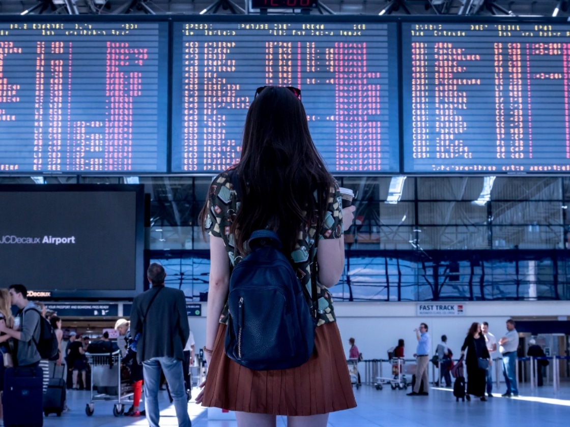 A traveller with a backpack reading an airport departure board | Luxury Travel SEO and Digital Marketing, Cevalon