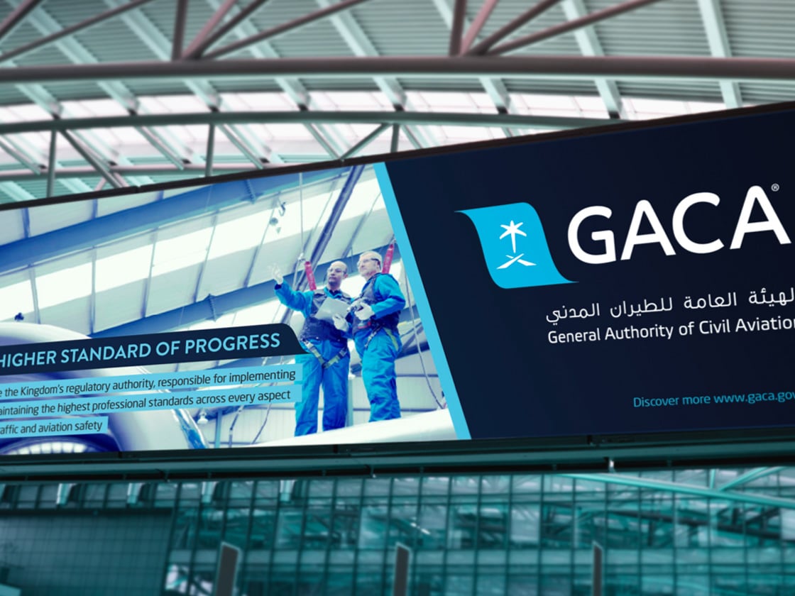A GACA airport billboard reading Higher Standard of Progress above a terminal concourse | Aviation Brand Strategy and Visual Identity, GACA