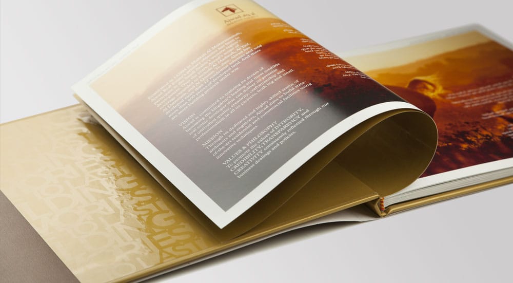 An open brochure with a translucent overlay page above gold foil endpapers | Real Estate Brand Communications, Saudi Arabia