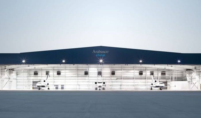 An Arabasco aircraft hangar lit at dusk with the bilingual wordmark on the fascia | Private Aviation Brand Strategy, Arabasco