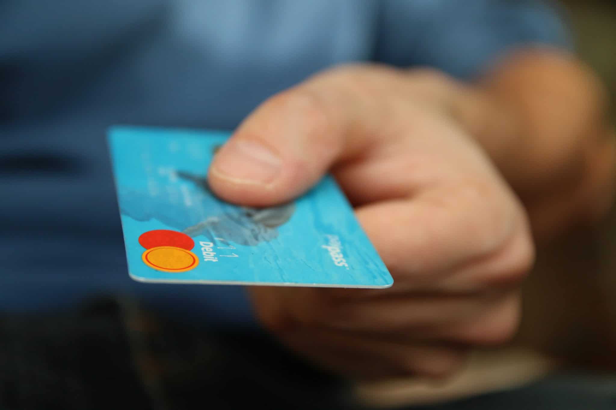 A hand holding out a contactless bank card, representing the shift in how customers use retail banking.