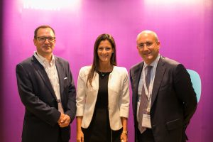Three guests photographed against the magenta Iridium Advisors backdrop at MEIRA 2017.