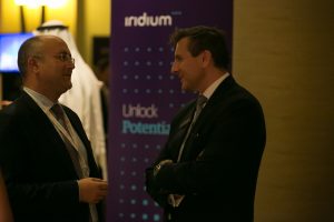 Two guests talking beside an Iridium Advisors Unlock Potential banner.