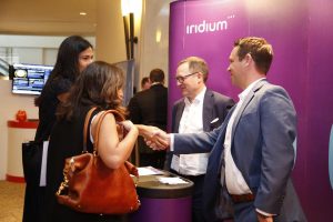 Guests shaking hands at the Iridium Advisors identity launch, the new branding behind them.