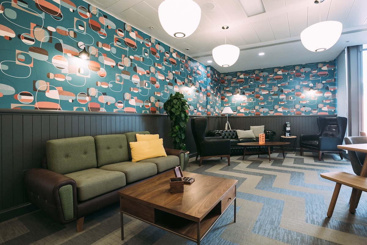 A WeWork members' lounge with a patterned feature wall, sofa seating and a low timber coffee table.