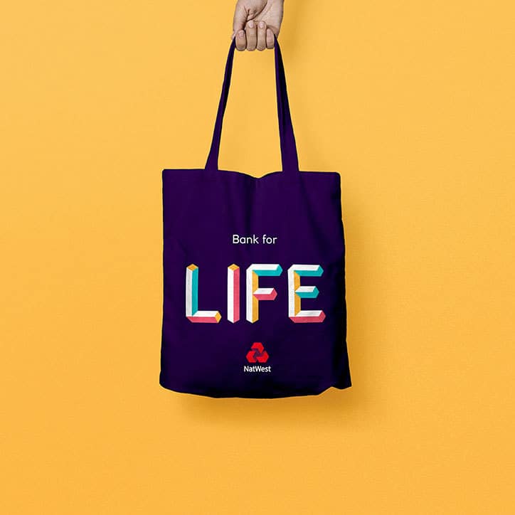A navy NatWest tote bag reading Bank for LIFE against a yellow background.
