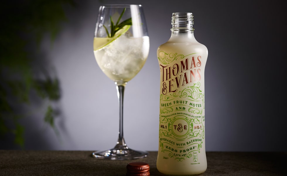 A Thomas and Evans No.1 zero-proof bottle beside a filled wine glass garnished with citrus and rosemary.