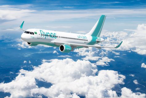 A flynas Airbus in the airline's teal and white livery, flying above a bank of cloud.