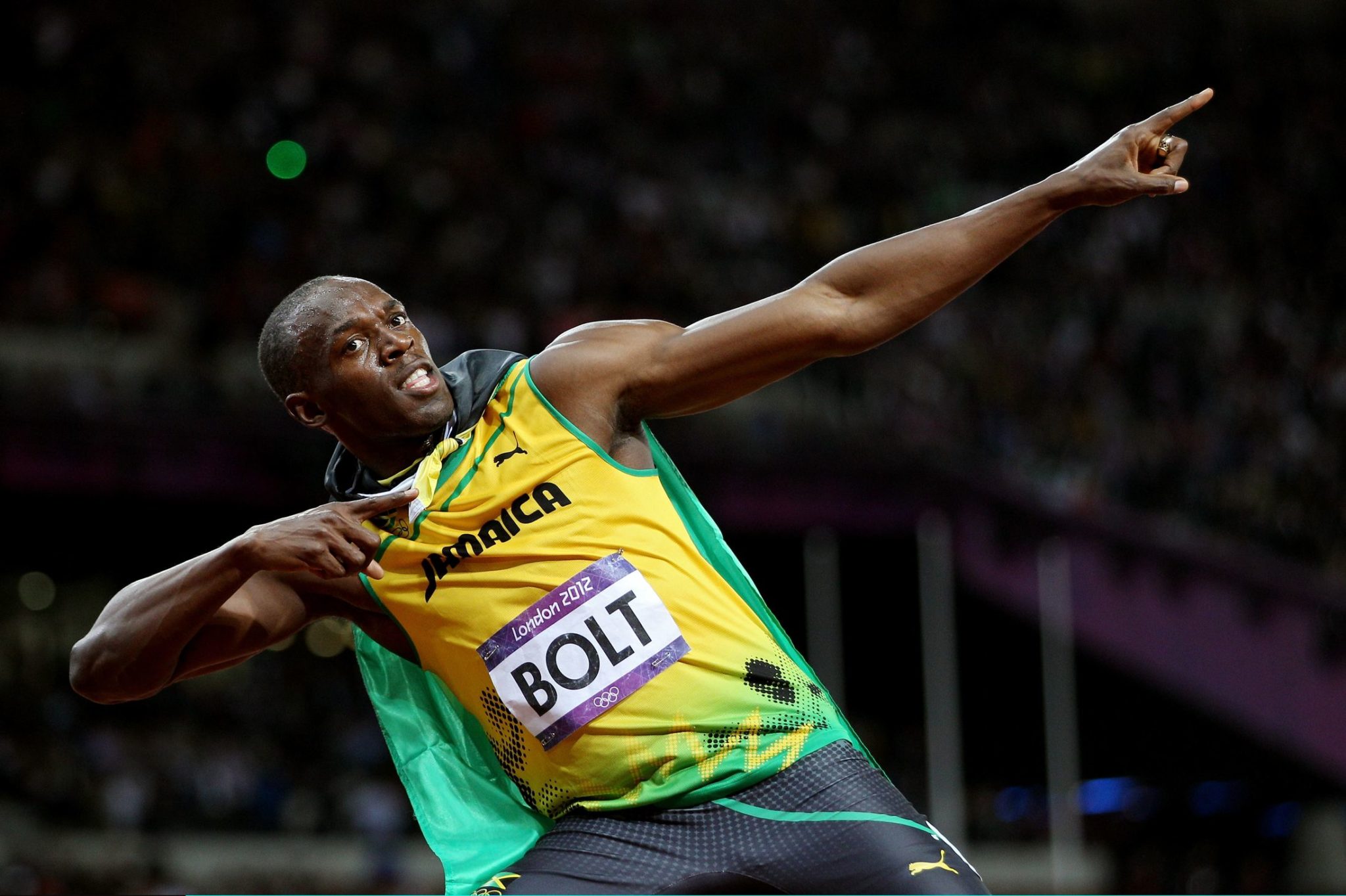 Usain Bolt performing his lightning bolt victory pose in Jamaican team kit after winning a race.
