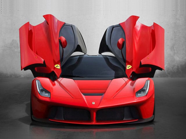 A red Ferrari LaFerrari photographed head-on with both butterfly doors raised.