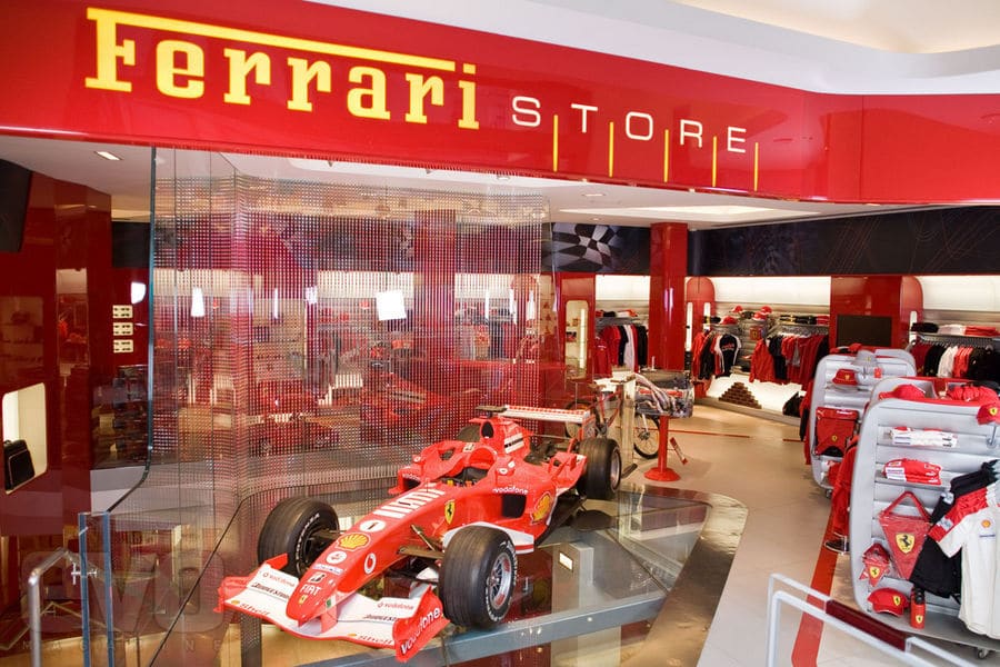 The entrance to a Ferrari Store, a Formula One car displayed behind the glass frontage.