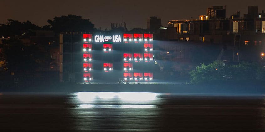 Audi's floating illuminated scoreboard installation on a river at night, displaying a live football score above the water.