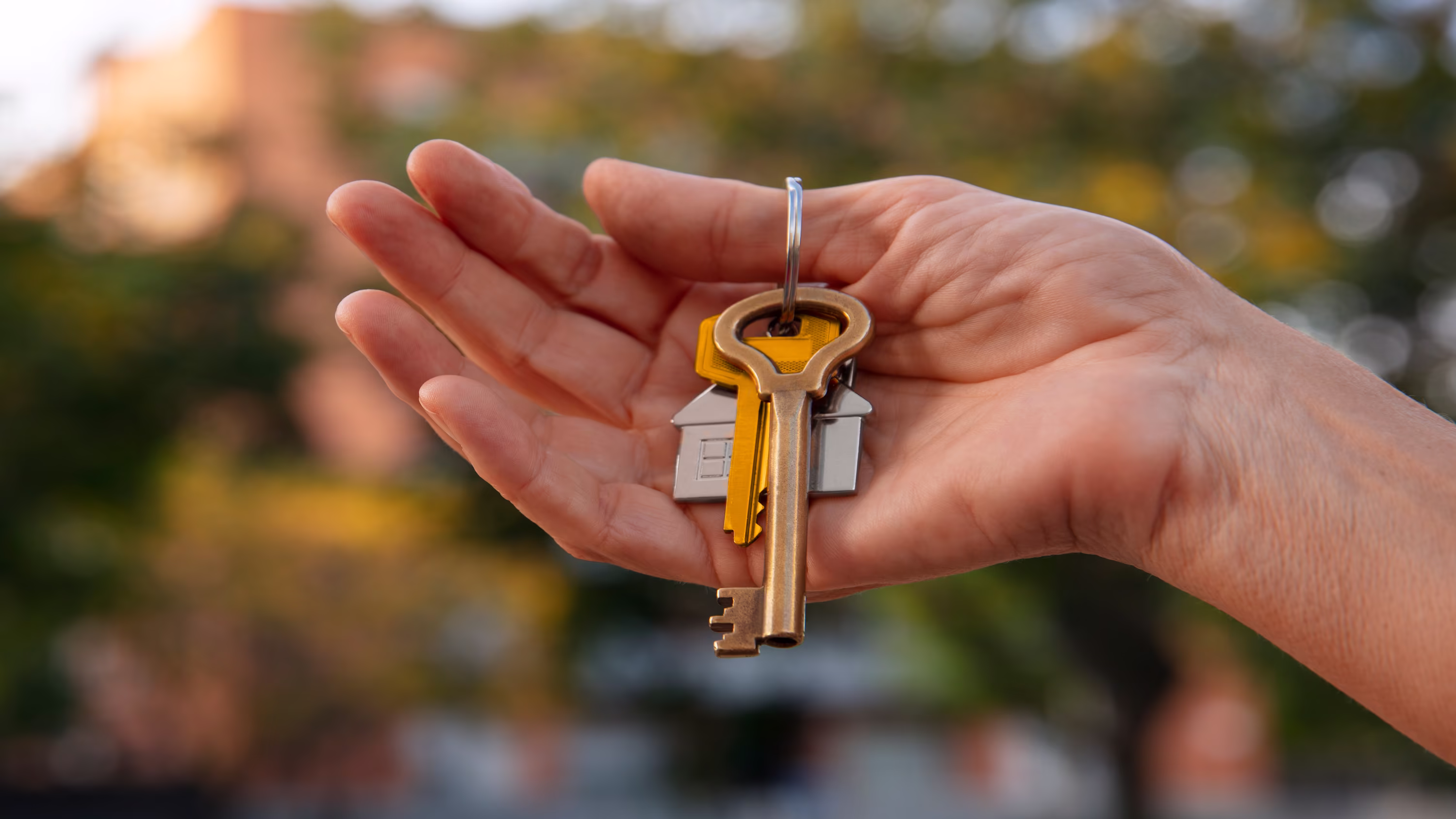 An open hand holding a set of house keys on a keyring | Property and Real Estate