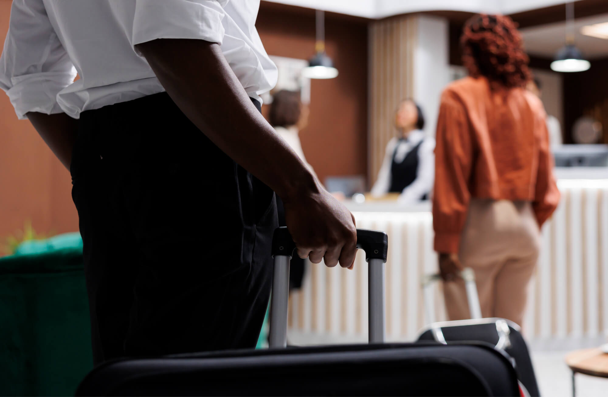 A hotel porter with a suitcase as a guest checks in at reception | Travel, Tourism and Hospitality