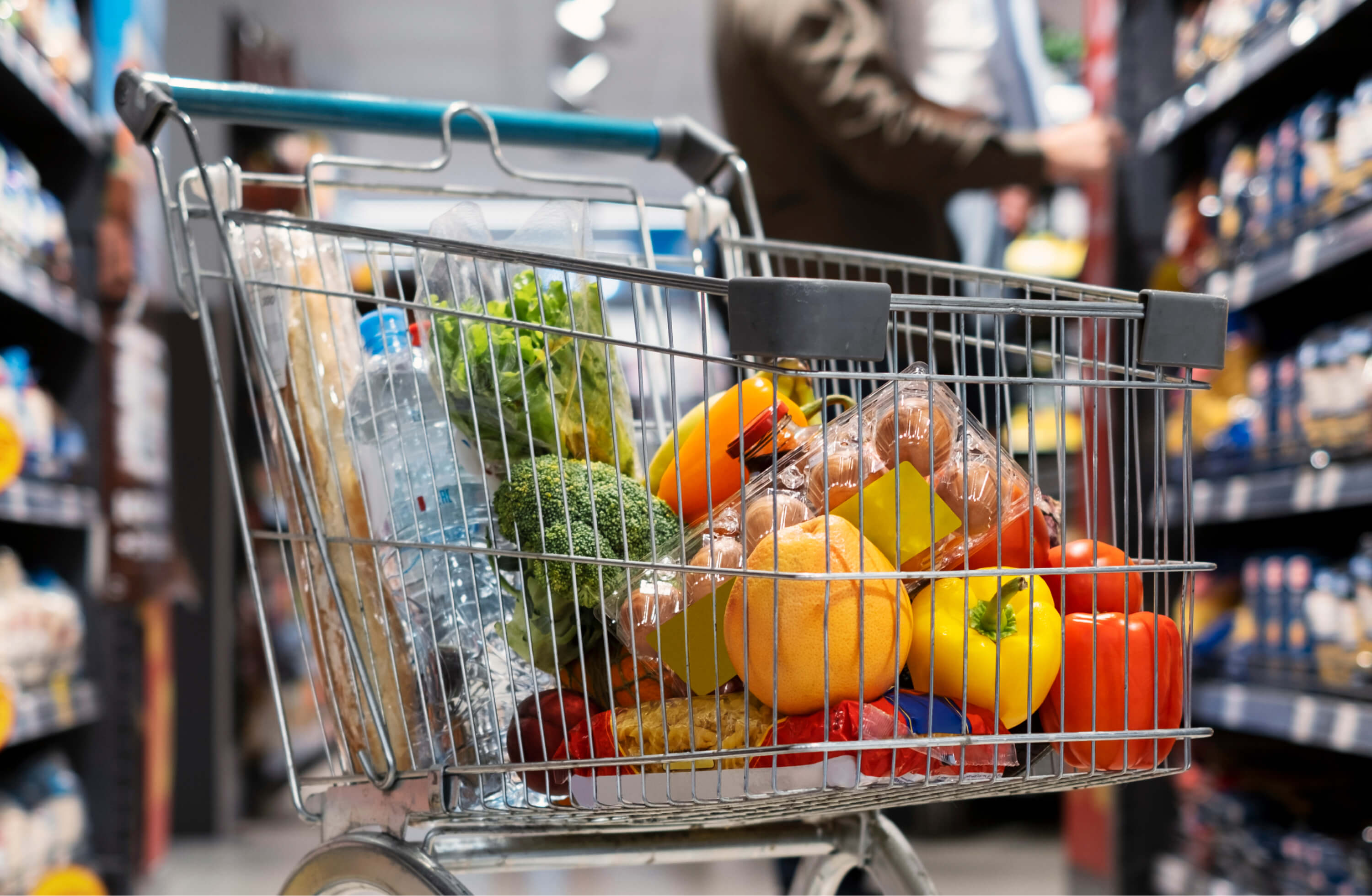 A supermarket trolley filled with fresh fruit and vegetables in a store aisle | Food and Beverage