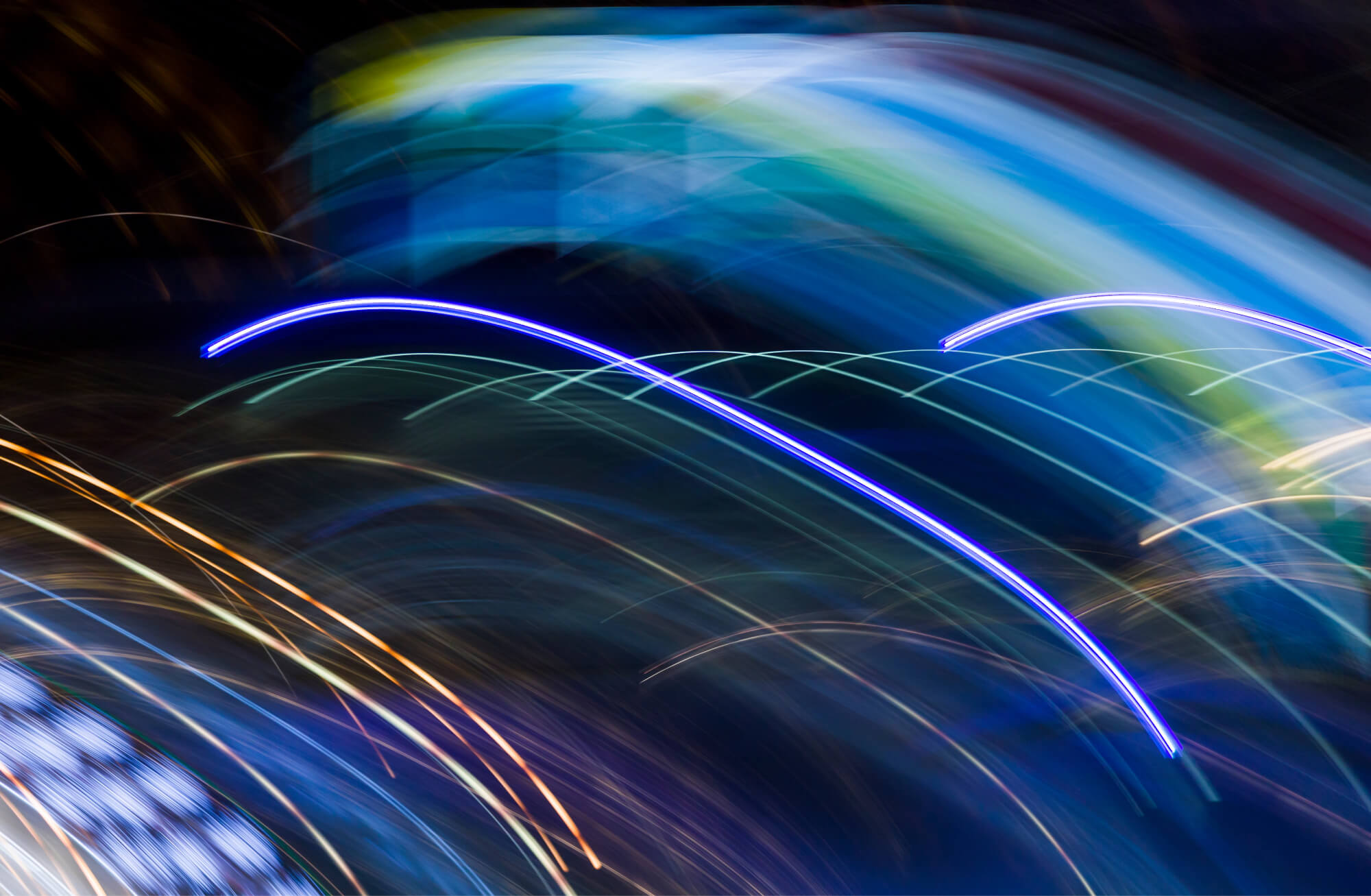 Long-exposure light trails curving in blue and violet against a dark background | Energy and Utilities