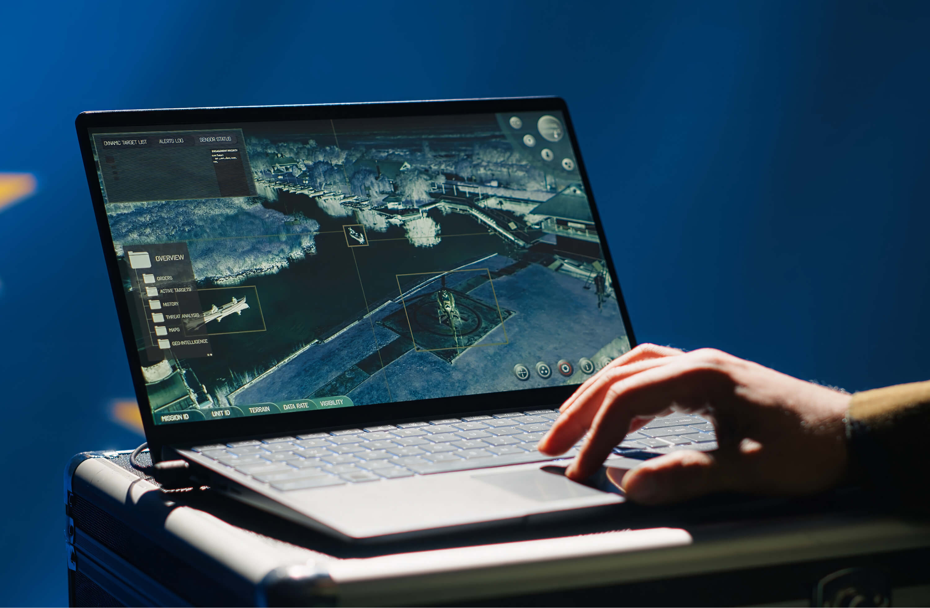 A hand operating a ruggedised laptop showing a satellite mapping interface | Defence and Intelligence