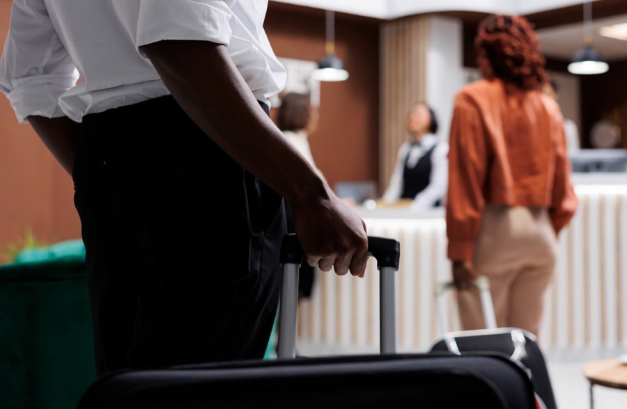 A hotel porter with a suitcase as a guest checks in at reception | Travel, Tourism and Hospitality
