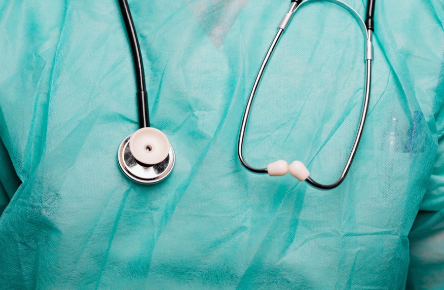 A stethoscope resting on a clinician's teal surgical scrubs | Healthcare and Life Sciences