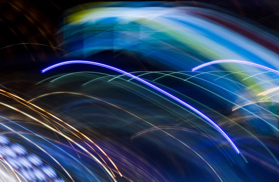 Long-exposure light trails curving in blue and violet against a dark background | Energy and Utilities