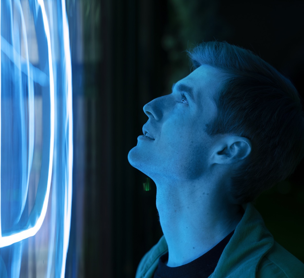 A man looking up into blue light in a darkened brand environment | Brand Experience