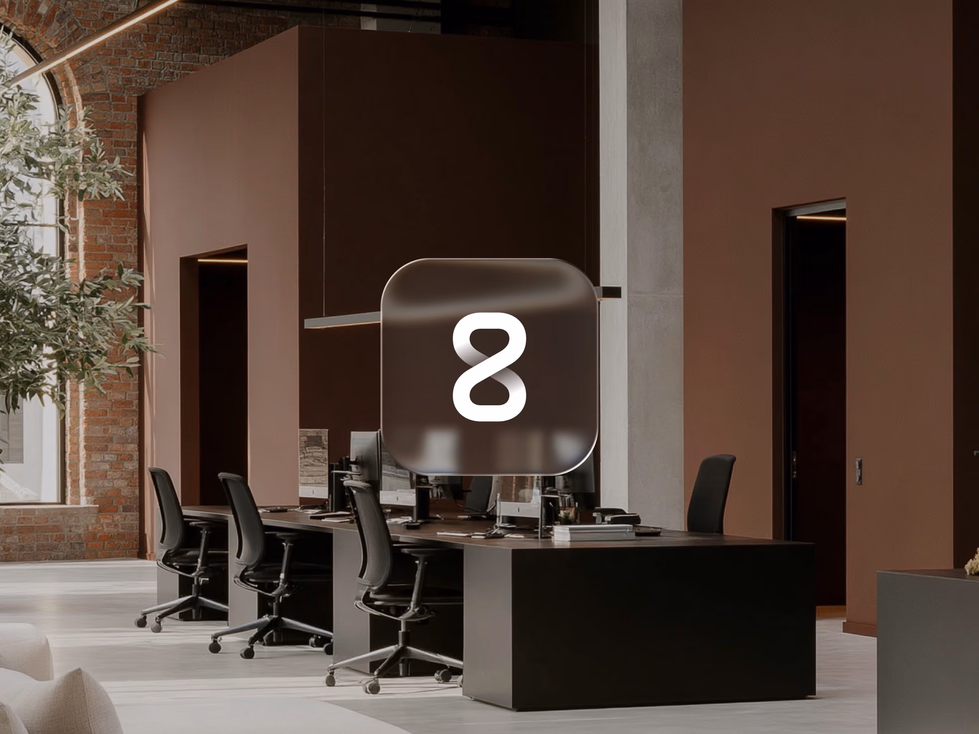 Modern office space with black desks, swivel chairs, computers, and a large window with brick wall.