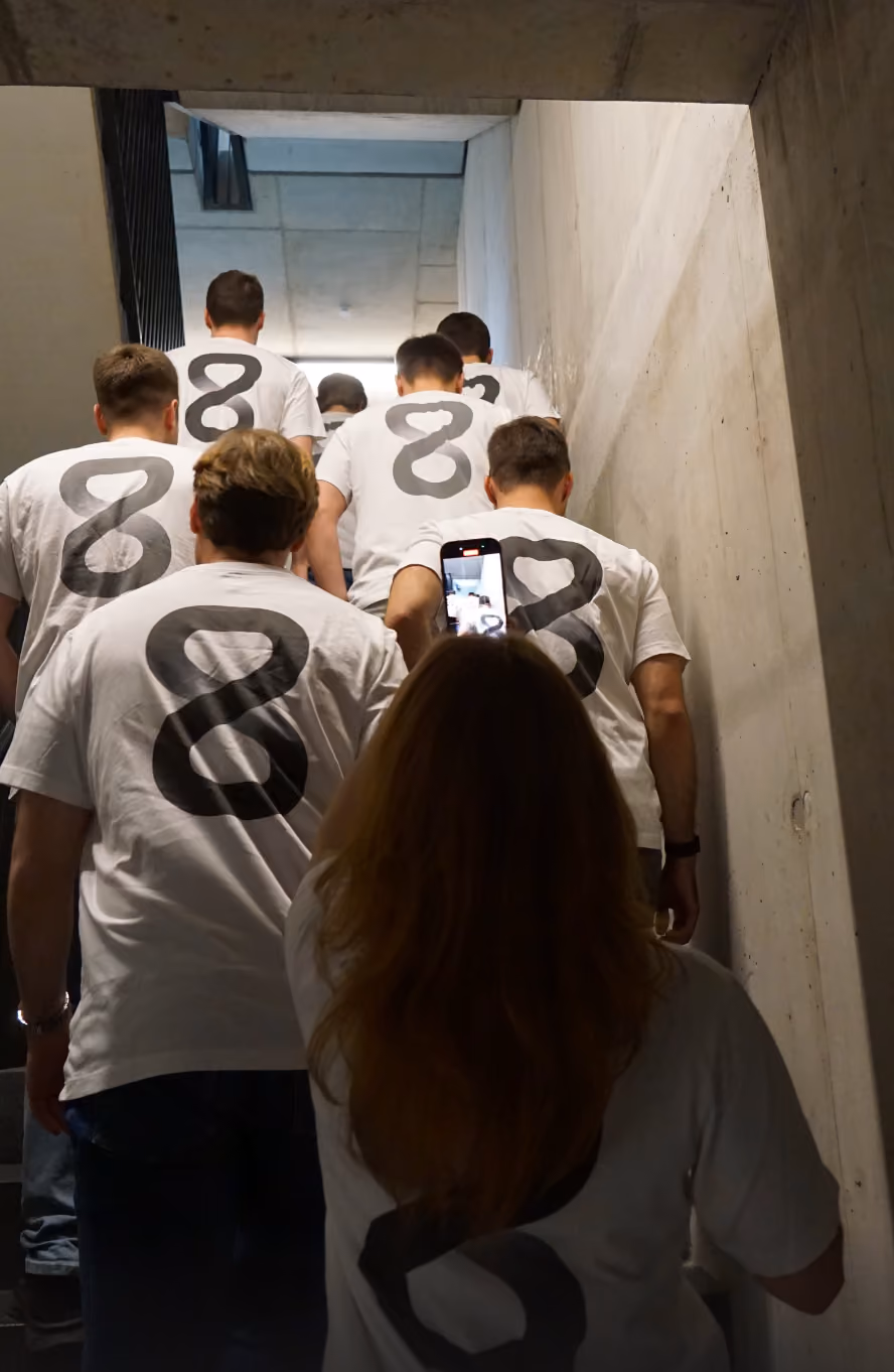 Group wearing white shirts with large black number 8 on backs, walking up a concrete stairway.