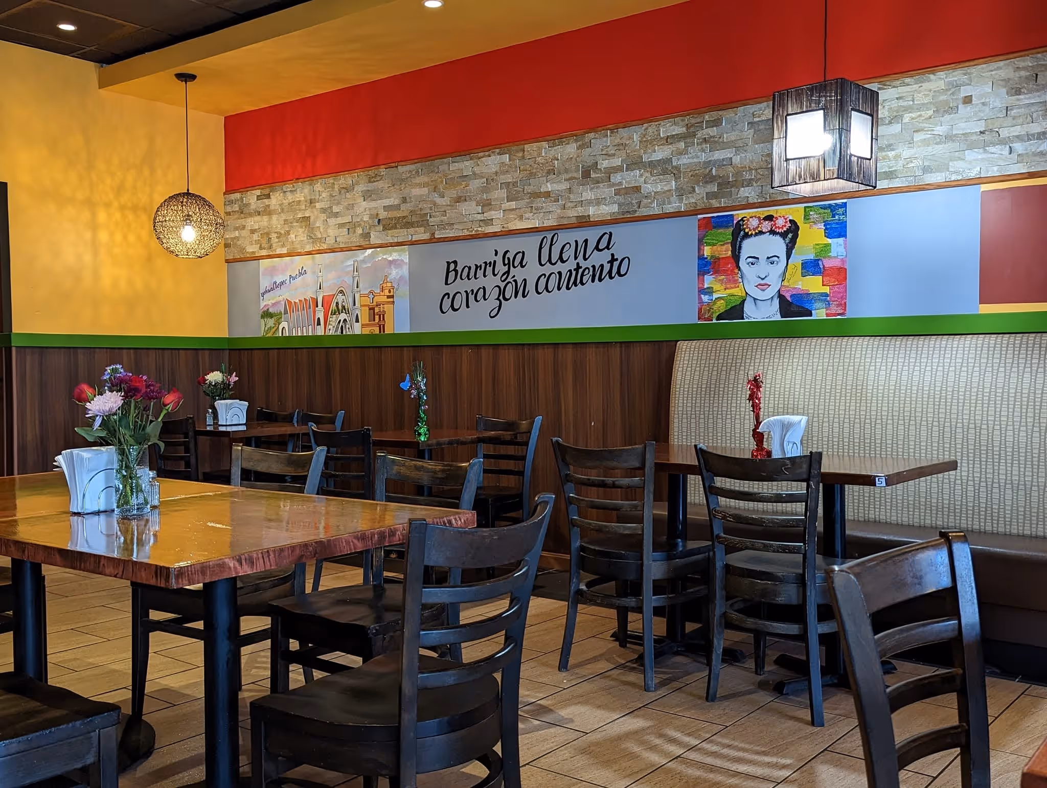 A restaurant with a red and yellow wall and a painting of a woman on the wall.