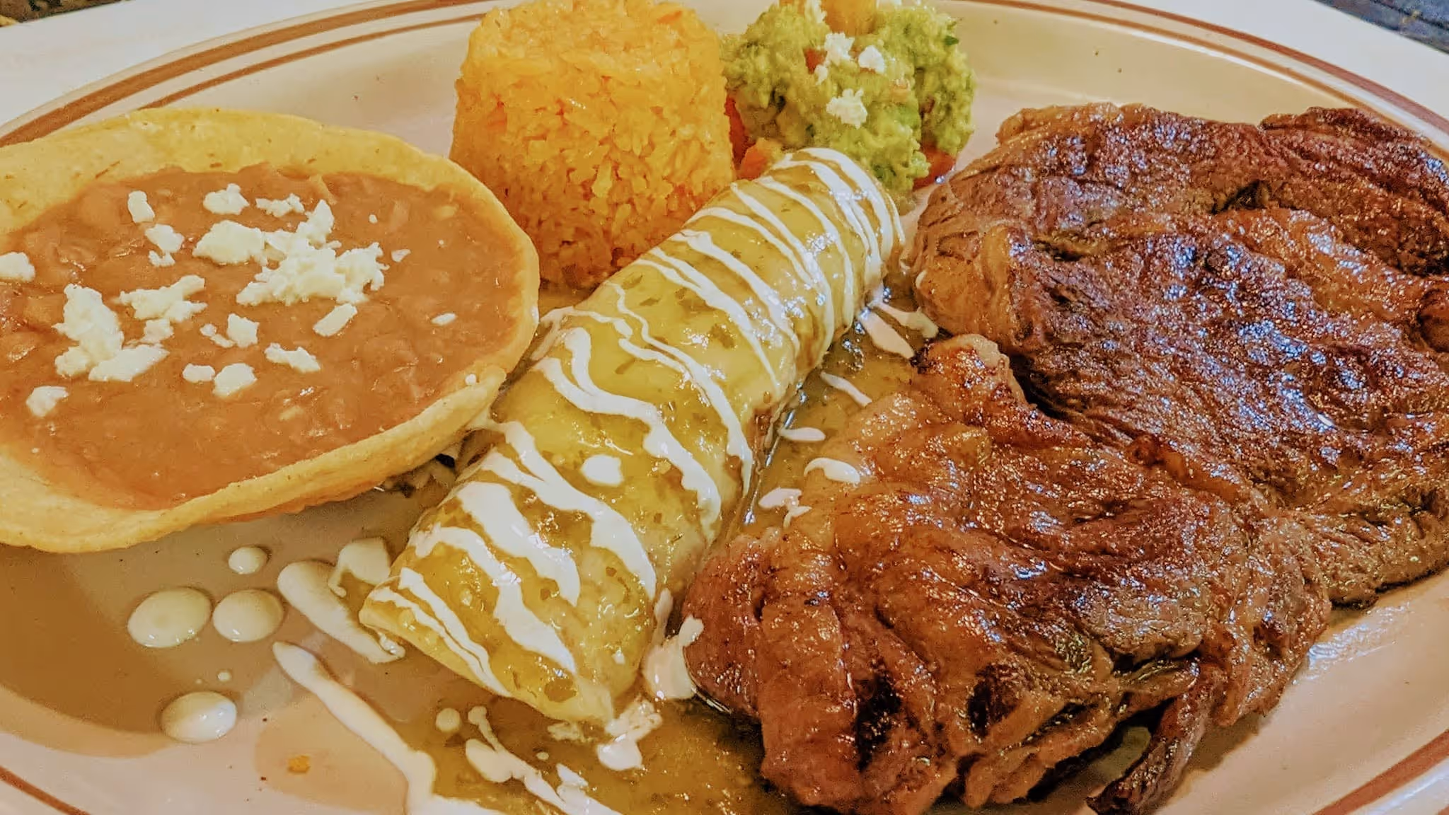 A plate of food with a meat dish and a burrito.