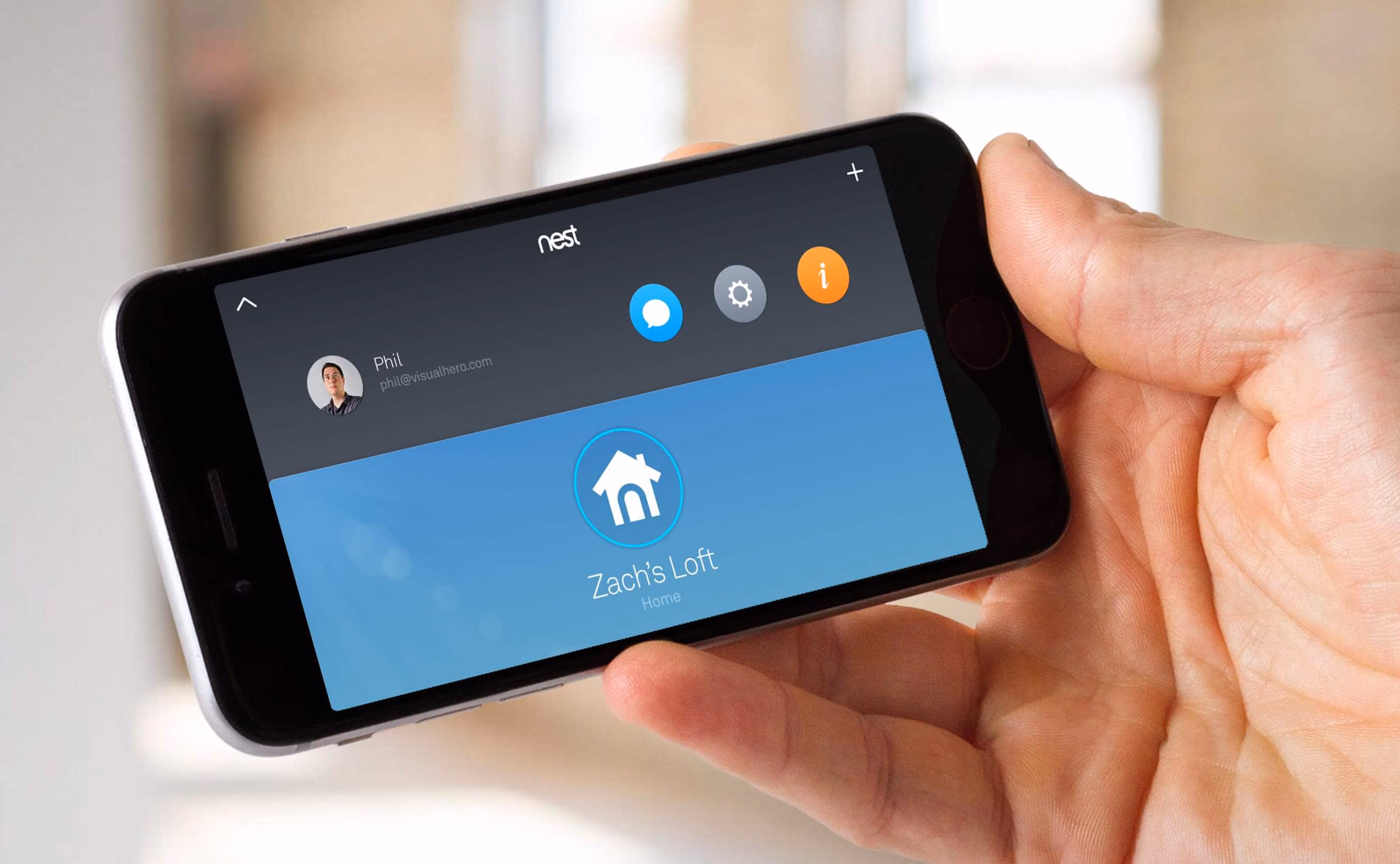 Hand holding a smartphone displaying the Nest app, showing a user profile named Phil and a home labeled "Zach's Loft".
