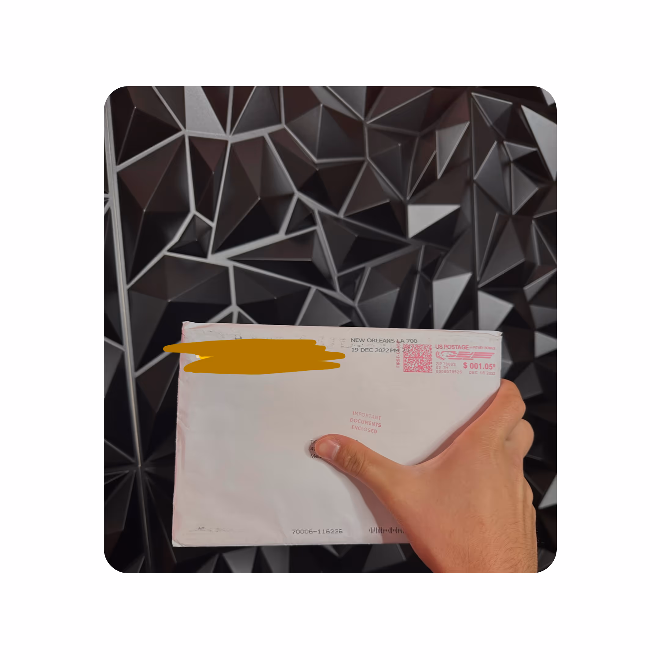 Hand holding a white envelope with red postage markings against a black geometric background.