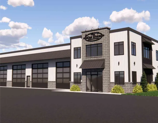Modern commercial building with multiple garage doors, large windows, and a sign above the main entrance.