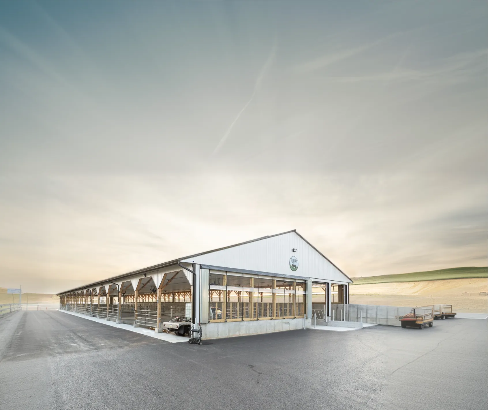 A large, open-sided agricultural building with a metal roof and concrete base.