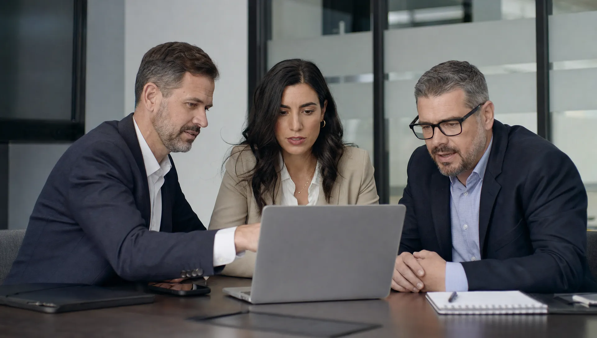A business owner, office manager, and IT consultant review an email security checklist on a laptop in a conference room.