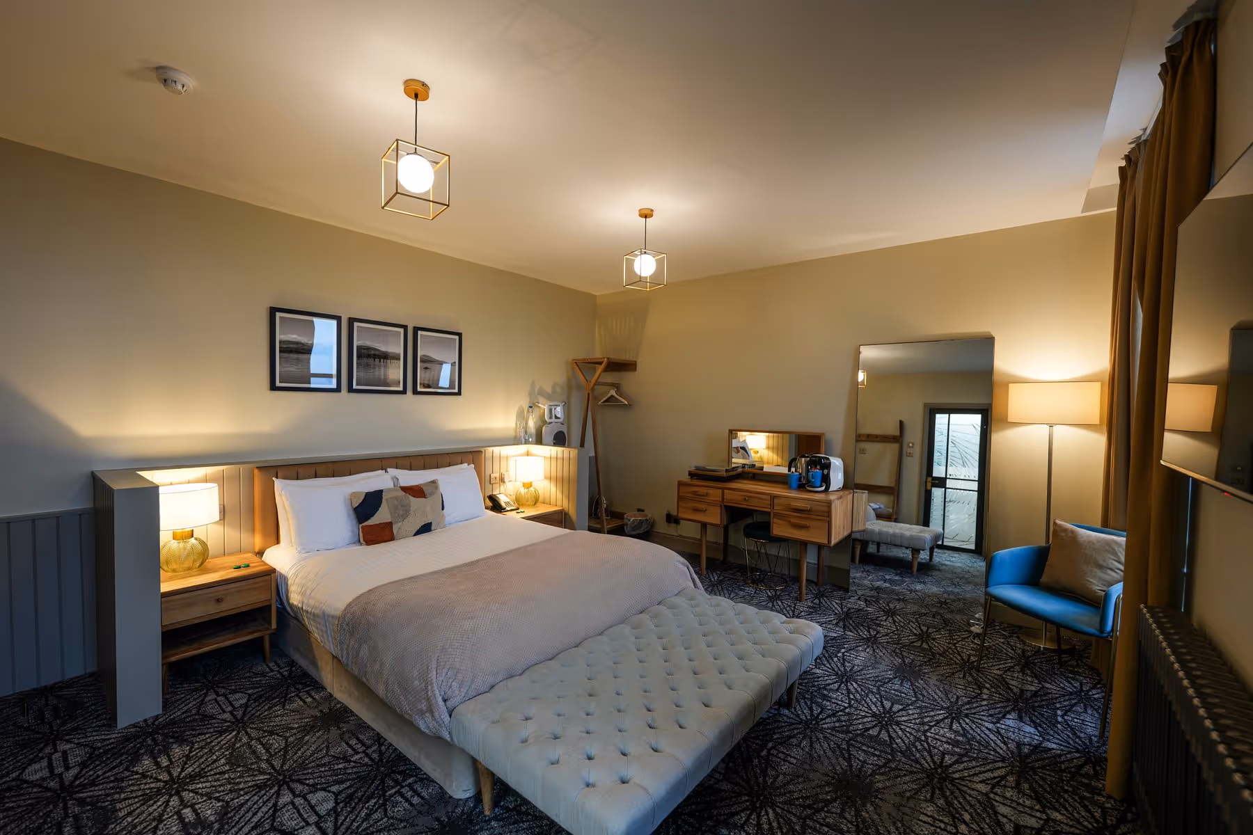 Spacious King with Sea View room at Riva Helensburgh showing the full room layout with kingsize bed, tufted bench, dressing table, and a large window overlooking the seafront.