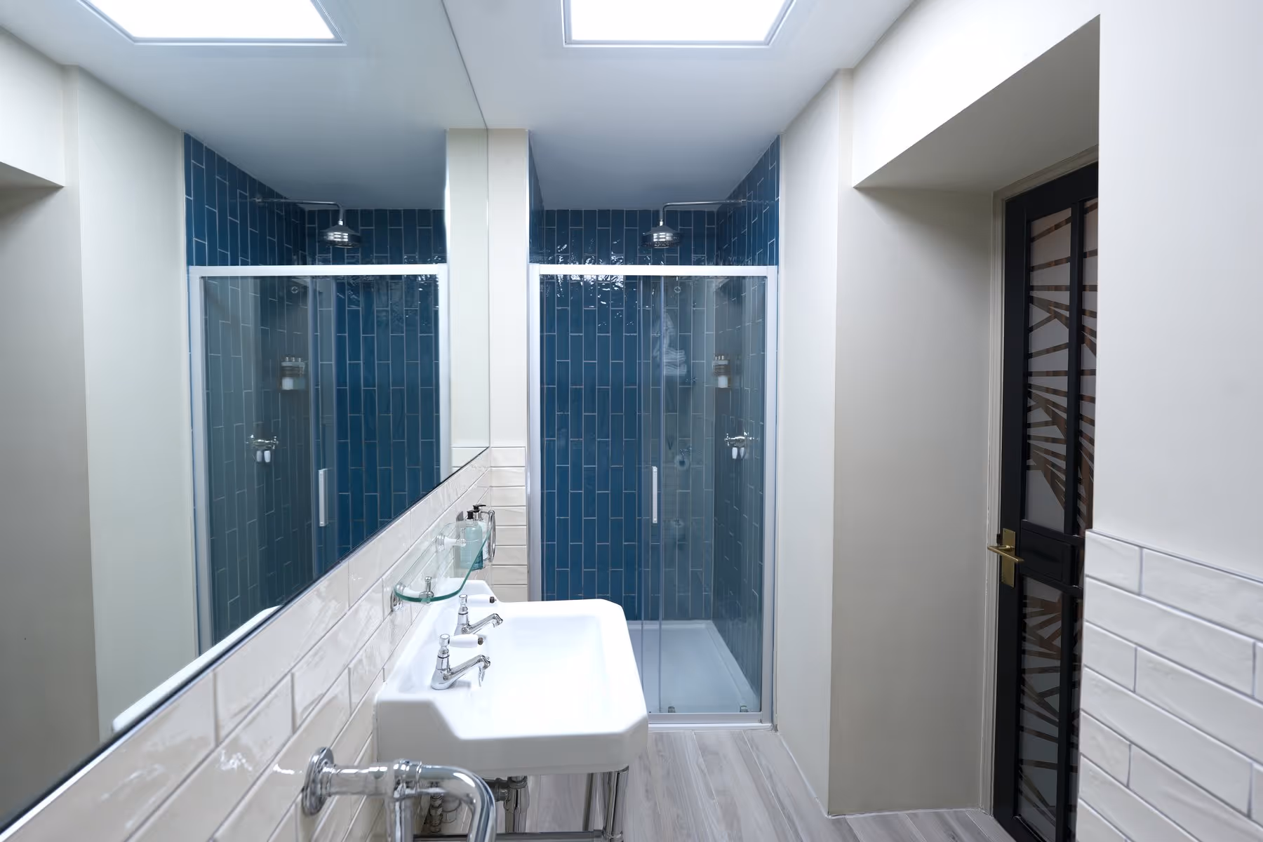 Family Room en-suite bathroom at Riva Helensburgh with white metro tiles, chrome fixtures, and a waterfall shower enclosure.