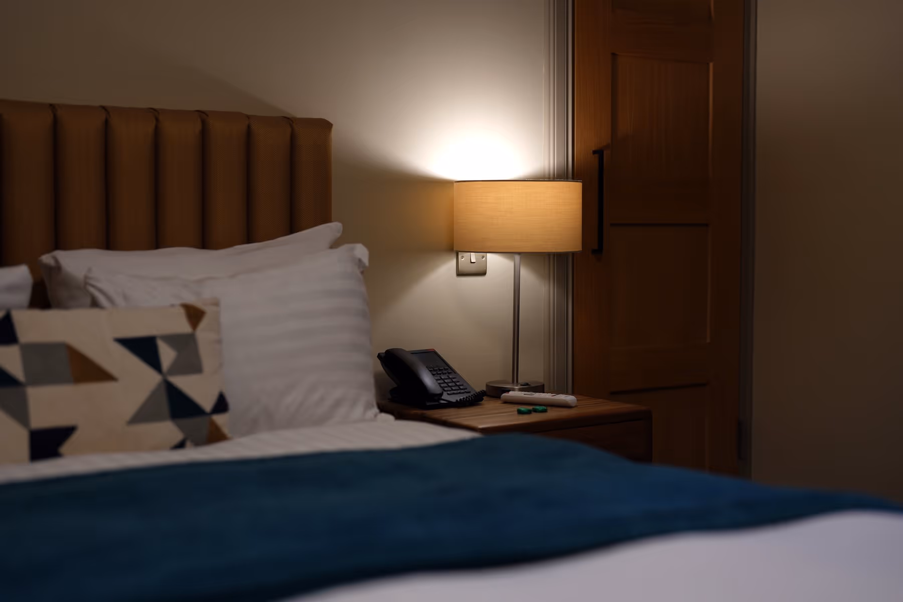 Double Room at Riva Helensburgh — wide angle showing the double bed, Scottish landscape prints above, and a window with gold curtains.