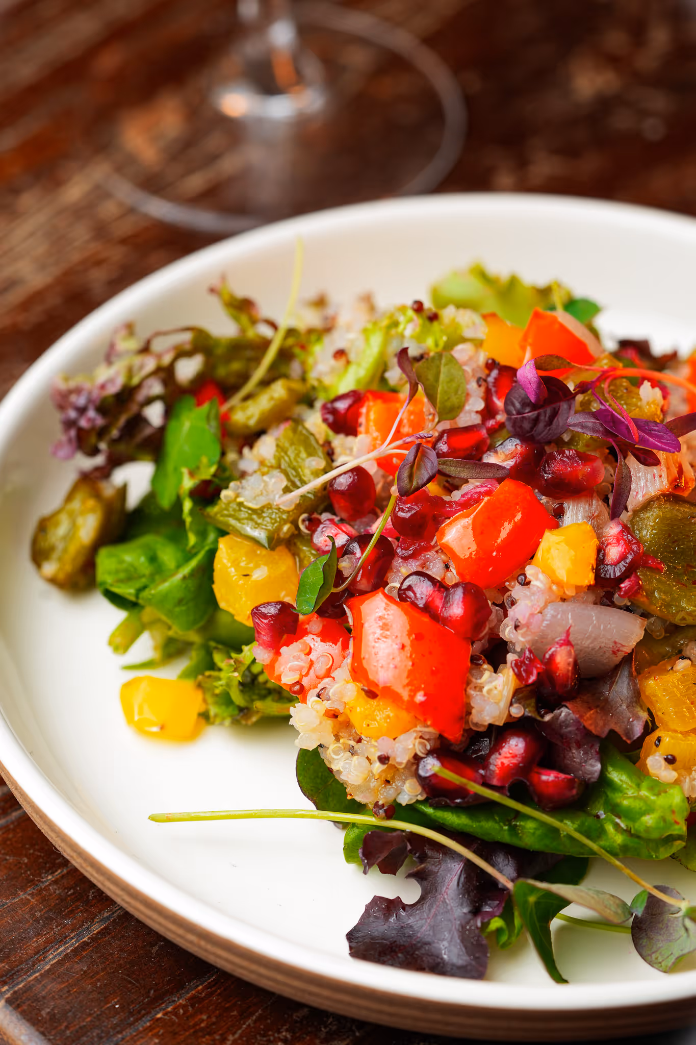 Close-up of a vibrant quinoa salad with roasted vegetables, pomegranate seeds, and mixed leaves at Santé Bistro, served in a white bowl.