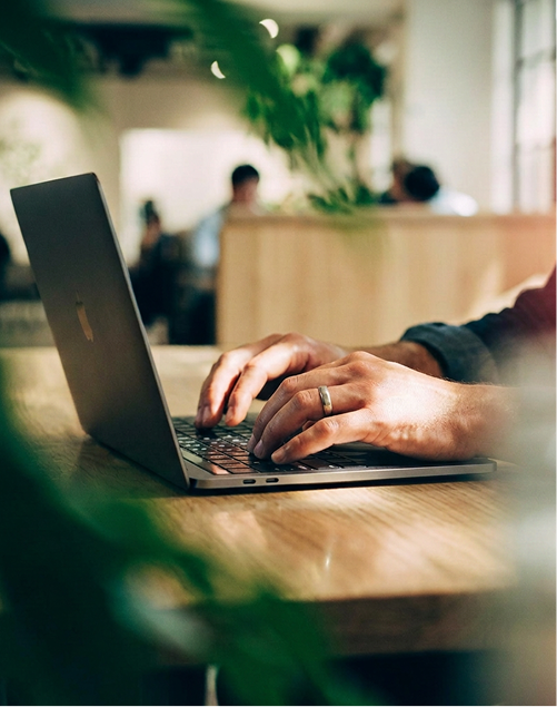 Hands typing on a laptop in a bright office