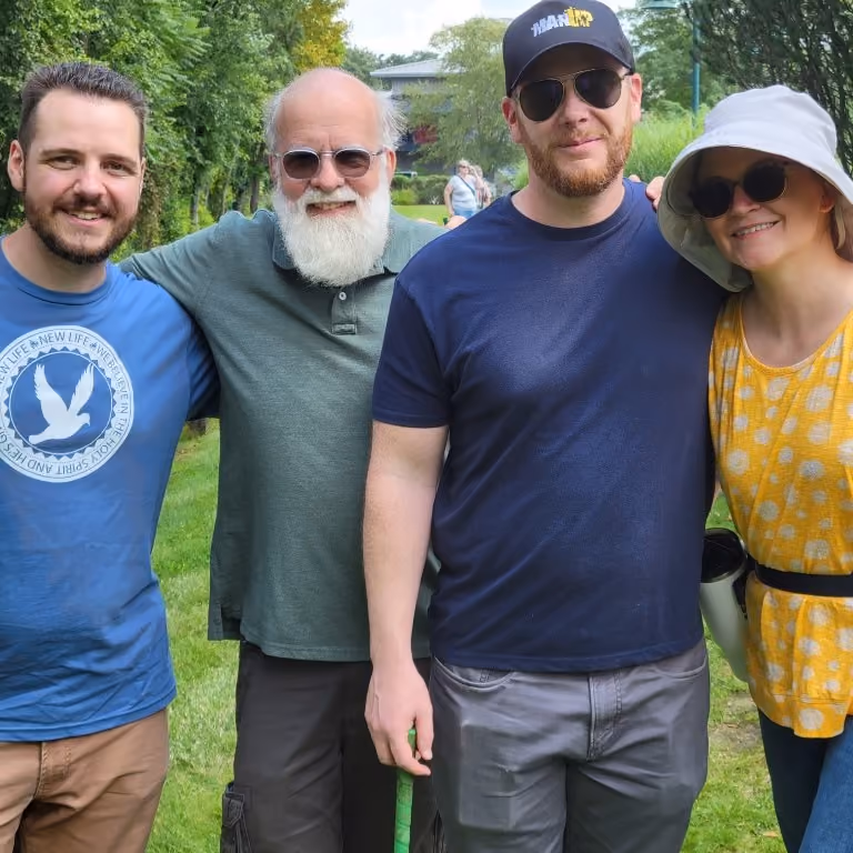 A group of four New Life members lean in with their arms around each others' shoulders and smile for a photo.