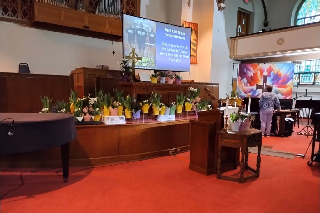 White, pink, purple, and yellow Easter flowers line the stage at the front of the Sanctuary.