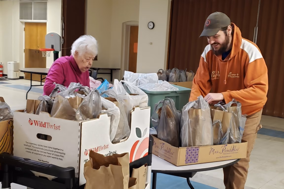 Volunteers Donna and Elijah pack bags to distribute through the Brown Bag Lunch ministry.
