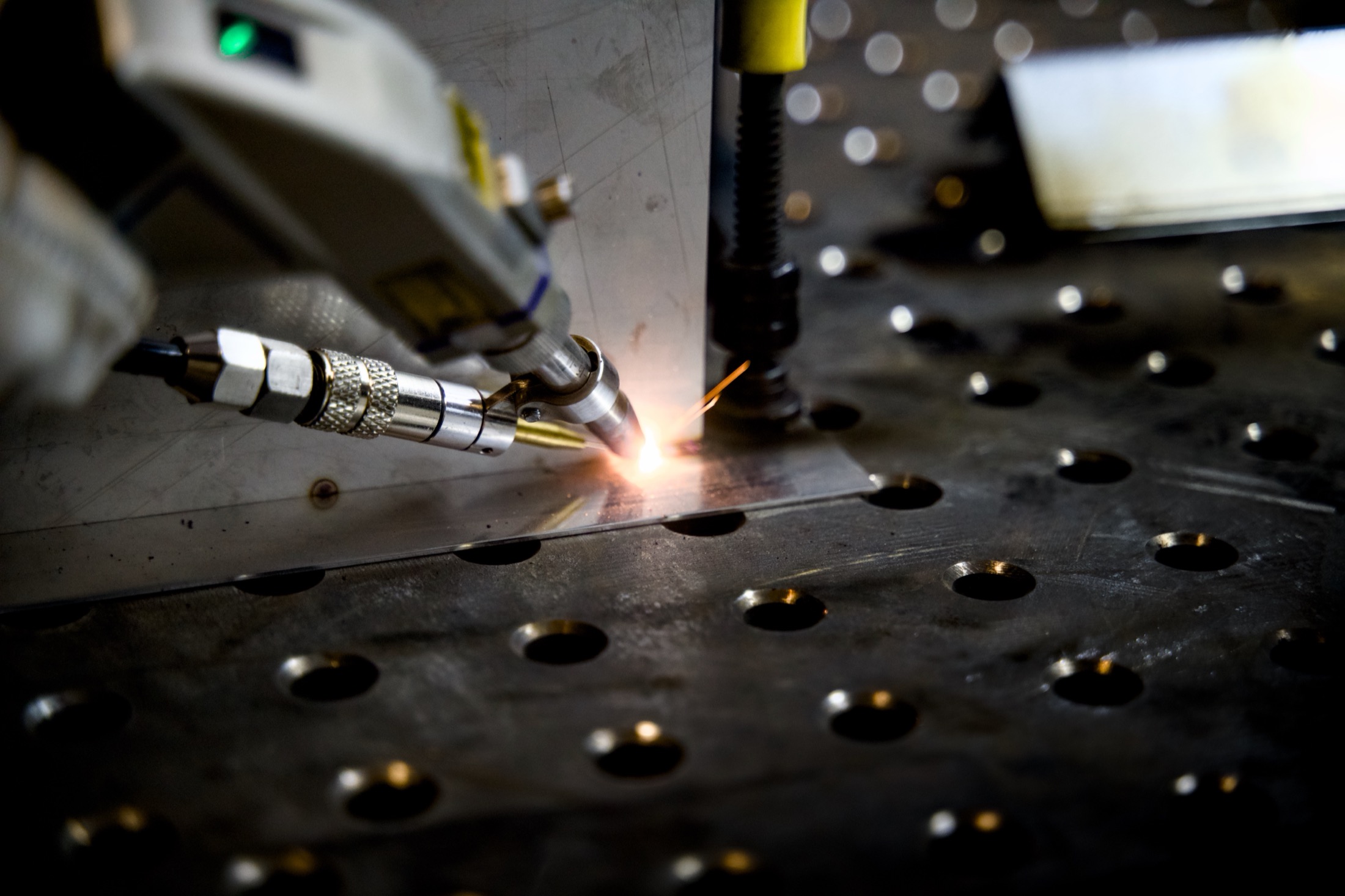 Laserschweißkopf setzt eine Naht an einem Stahlbauteil auf dem Schweißtisch