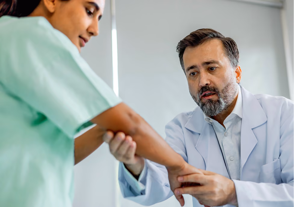 Male doctor examining a female patient's wrist in a medical office.