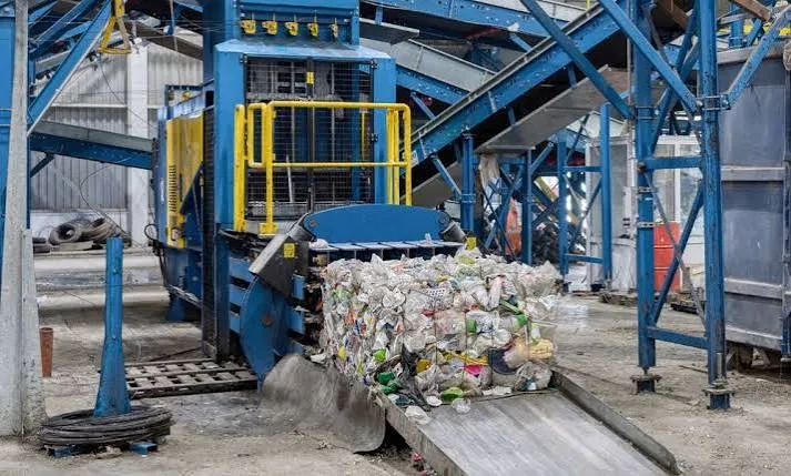 Industrial compactor loading compressed recyclables at a processing facility